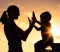 Silhouetted mother and child high five at sunset, symbolizing healing after divorce and change together