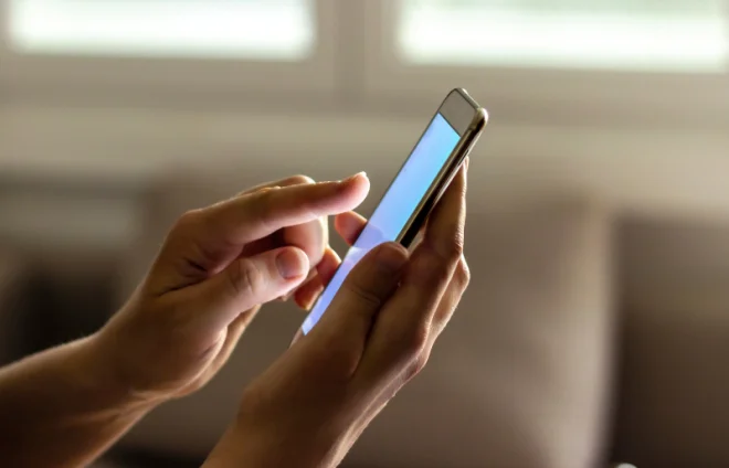 Hands hold smartphone with blank screen, sending message to lawyer about divorce paperwork updates now