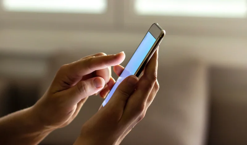 Hands hold smartphone with blank screen, sending message to lawyer about divorce paperwork updates now