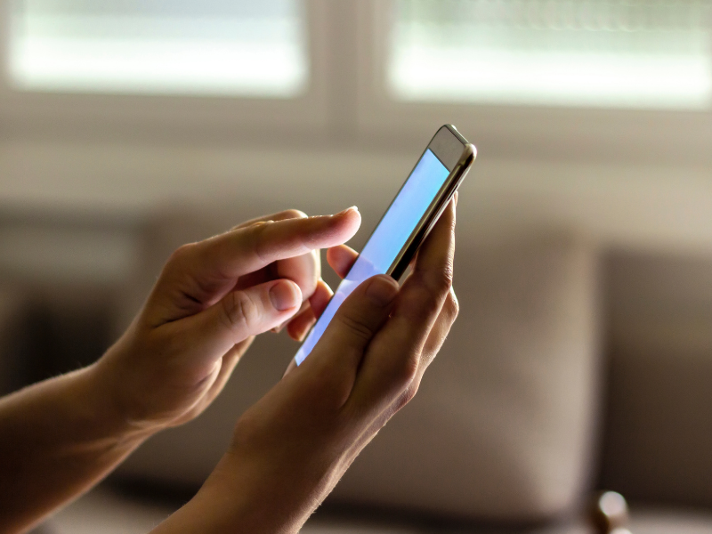 Hands hold smartphone with blank screen, sending message to lawyer about divorce paperwork updates now