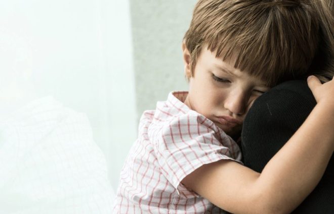 Young child hugging an adult, reflecting emotional strain, insecurity, and the impact of family conflict