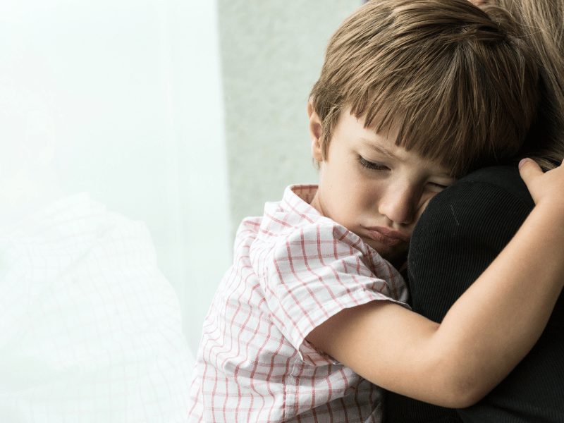 Young child hugging an adult, reflecting emotional strain, insecurity, and the impact of family conflict