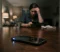 Smartphone on a table in the foreground with a blurred person sitting in the background looking stressed at night