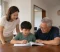 Grandparent Child Support A child studies with a grandparent at home while a parent watches nearby, illustrating family support after meeting a divorce lawyer.