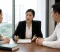 A female lawyer explains legal matters to a couple seated across from her at an office table