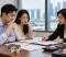 An Asian couple meets with a female legal professional in a Singapore office to review financial documents, property assets, and legal paperwork related to their divorce